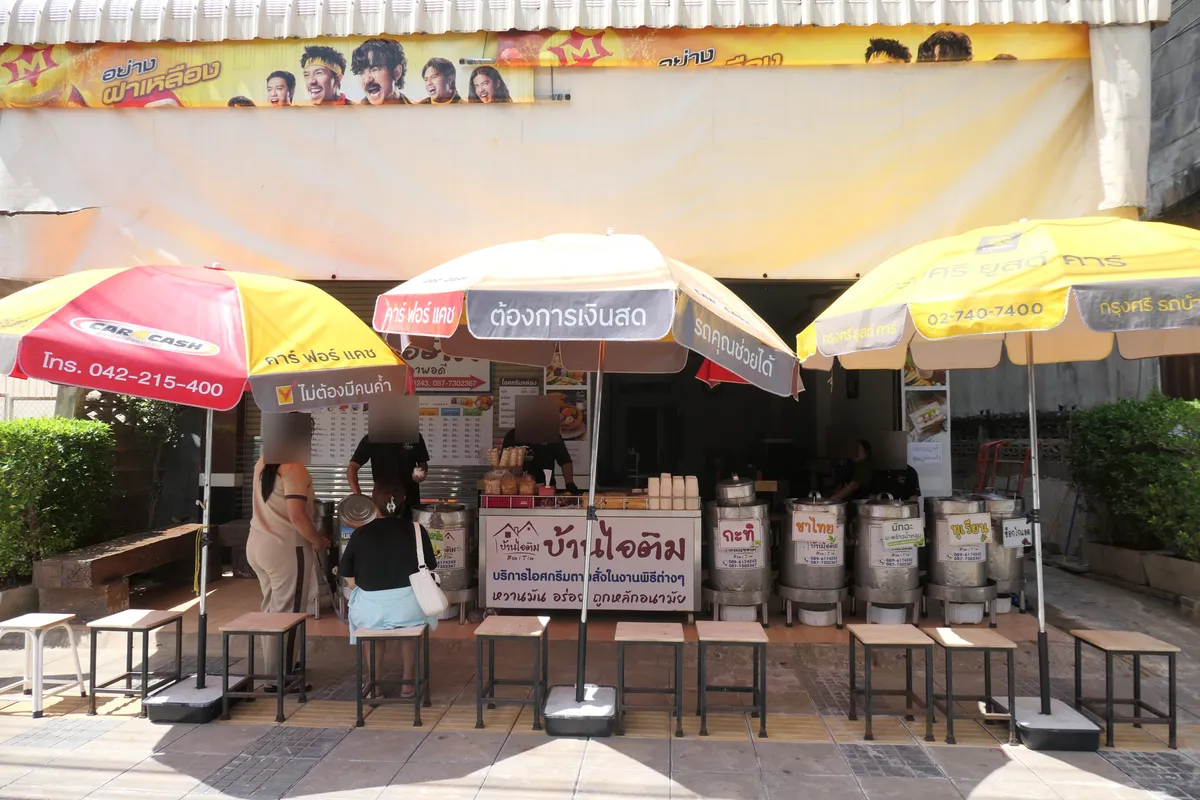 Stainless steel tubs of ice cream in several flavours, labelled coconut, Thai tea, matcha and durian, with customers waiting at the counter