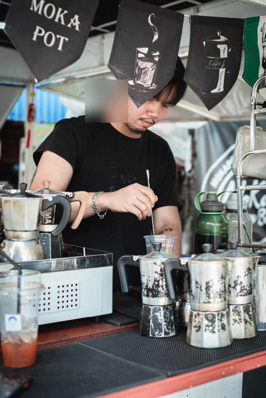บาริสตายืนทำกาแฟบนเคาน์เตอร์ หม้อ Moka Pot วางอยู่ข้างหน้า
